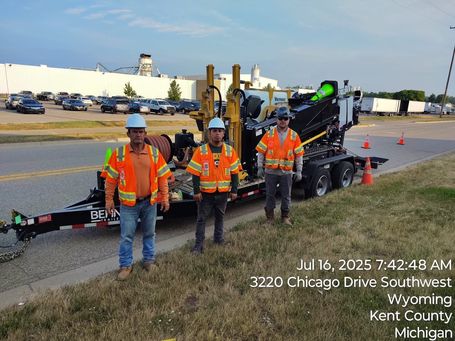 Three INCORED crew members in hard hats and safety vests beside a drill rig in Wyoming, Michigan