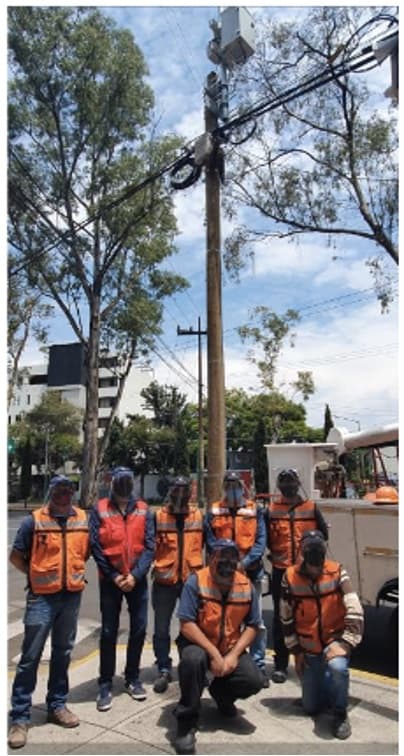 INCORED field crew with safety vests and hard hats beside a utility pole in northern Mexico